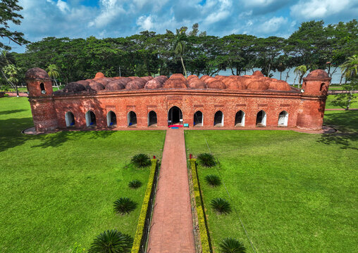Aerial view of the historic Sixty Dome Mosque with its red brick walls and multiple domes surrounded by lush green lawns and trees in Bagerhat, Khulna Division, Bangladesh.