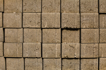 Fototapeta premium Close-up of stacked concrete paving blocks with rough industrial texture and geometric pattern. Construction material background for architecture and infrastructure themes