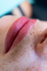 Naklejka premium Extreme close-up of full lips with permanent makeup, lip blush tattoo, beauty macro