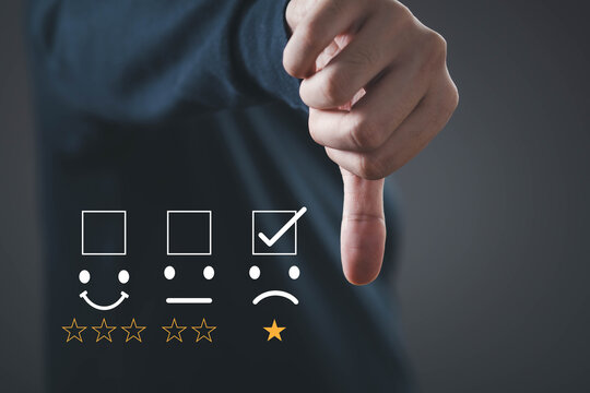 Business hand giving negative feedback on customer satisfaction survey, selecting low rating icon, symbolizing poor service experience, review management, quality assessment, and business performance.