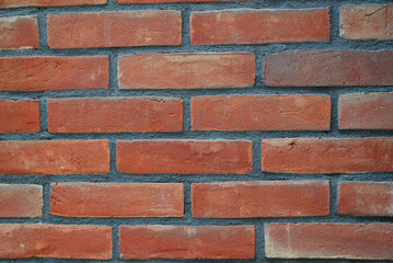 Fototapeta premium red brick wall with visible mortar lines and rough texture. Detailed masonry background with natural color variations, ideal for architecture, construction, urban design, wallpaper