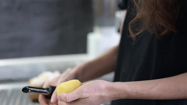 Woman peeling yellow potato with kitchen peeler during healthy meal cooking Full HD video