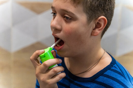 Child uses green inhaler to take medication indoors during a health routine