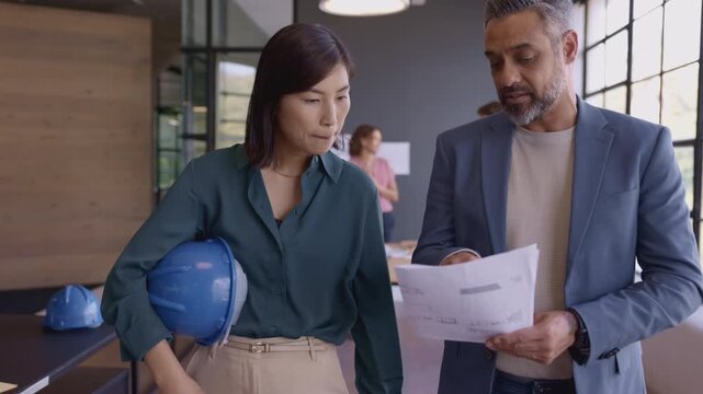 Architects discussing project while walking in the office
