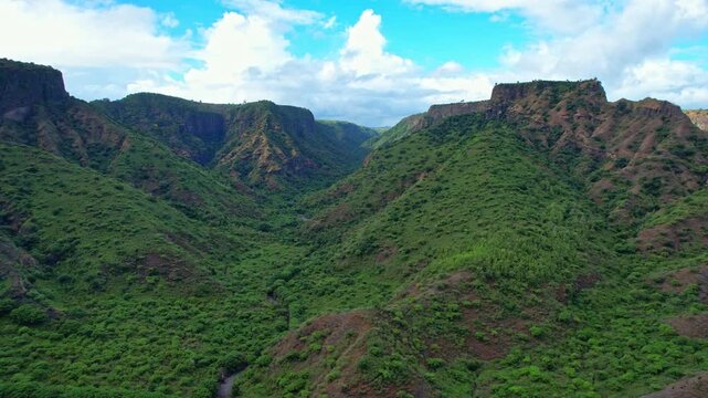 Aerial drone footage of a wild canyon valley in Wera Ambalawi coastal road, with blue sky and clouds, in Bima regency, Sumbawa island, Indonesia