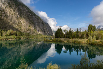 Obraz premium Peaceful Alpine Lake Buclet surrounded by mountains under a blue sky and few clouds in the French Alps, Isère