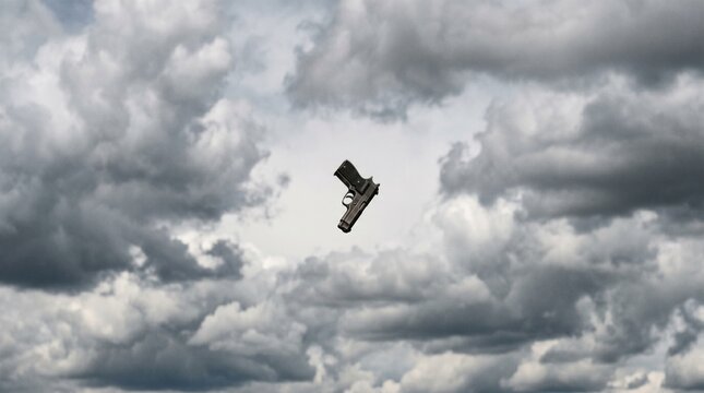 A single handgun floating in the air against a backdrop of dramatic, dark, and cloudy sky