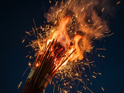 A blazing torch emitting sparks against a dark night sky.