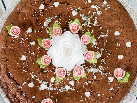 G&acirc;teau fondant au chocolat d&eacute;cor&eacute; de fleurs en sucre roses et perles blanches vu du dessus