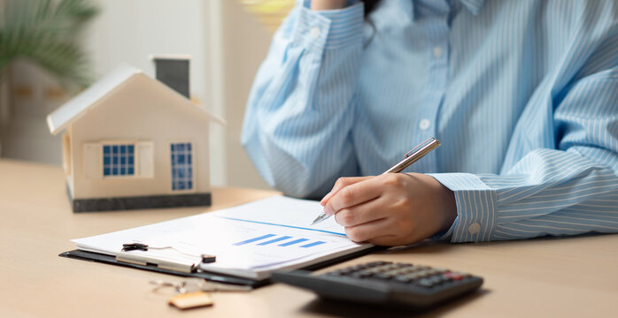 Businesswoman reviewing mortgage and real estate documents while talking on phone, representing home loan planning, property investment, financial analysis, and housing finance management.