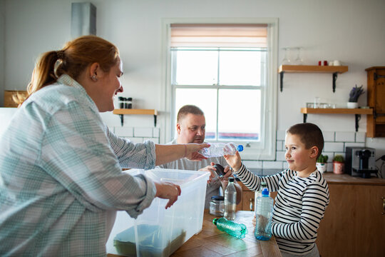Family sorting plastic bottles for recycling in home kitchen
