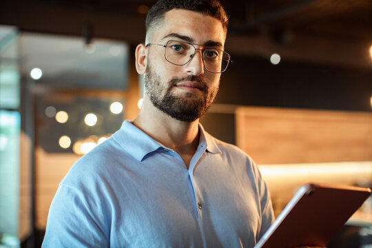 Confident young man with tablet in modern office