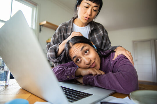 Two adults at home comforting a stressed woman working on a laptop