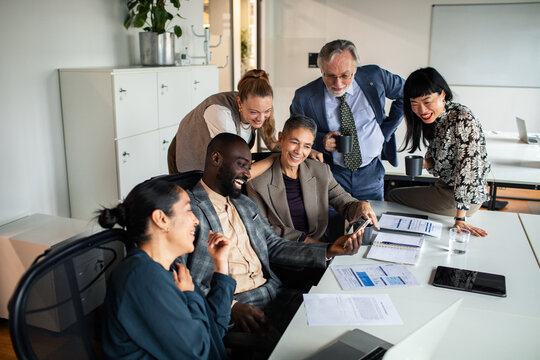 Diverse business team reviewing smartphone in office meeting