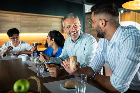 Coworkers enjoying lunch together in modern office kitchen