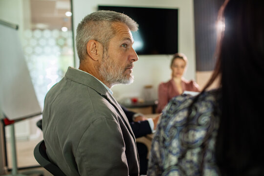 Mature manager listening during team meeting in office