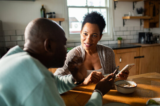 Couple talking over breakfast in home kitchen