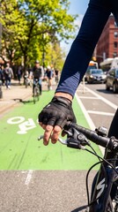 Naklejka premium A cyclist's hand grips the handlebar, navigating a vibrant green bike lane amidst a bustling city street, a dynamic urban scene.