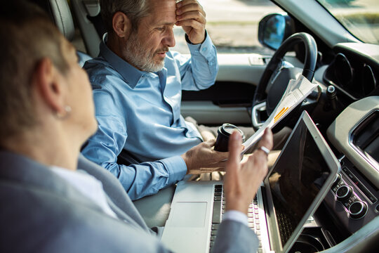 Business colleagues reviewing financial report in car