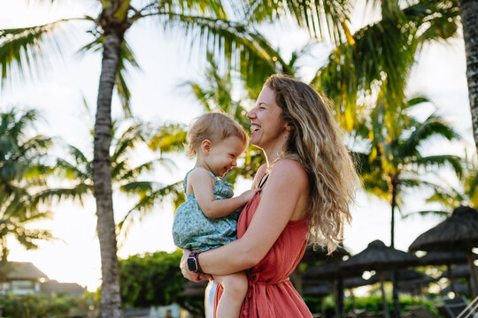 Mother embracing her little daughter in tropical beach resort.