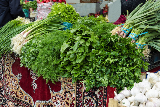 Fresh herbs and greens piled on a carpet-covered stall at Siab bazaar in Samarkand. Ideal for food, travel, and cultural content about Central Asian markets.