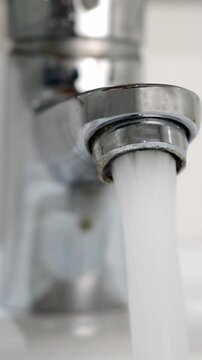 Tap water running wastage from faucet in hand washing sink, ceramic basin in water closet, public wc room,school bathroom or home for saving ecological and environmental conservation awareness concept