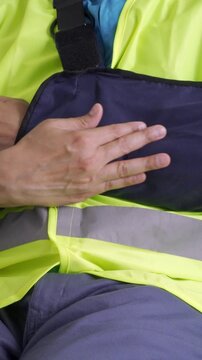 Close up of a repairman grabbing his painful bandaged arm on a couch at home