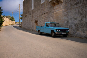 Vintage blue pickup truck parked by an old stone wall on a rural road in Malta © jirka