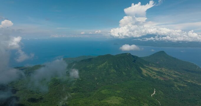 Top view of mountain with lush green forest in Camiguin Island. Blue sky and clouds. Philippines.
