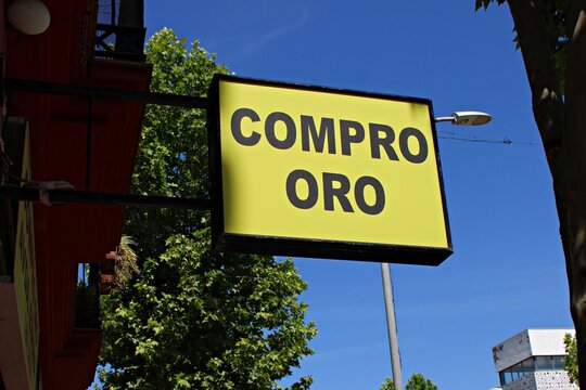 &ldquo;Compro Oro&rdquo; gold buying sign on a Spanish storefront facade, advertising precious metal purchasing services in an urban street setting under blue sky in Andalusia, Spain
