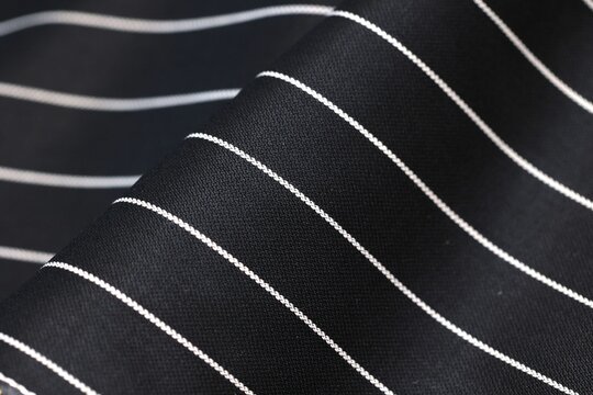 Luxury black pinstripe suit fabric. Ultra-premium bespoke pure wool textile for high-end tailoring. Elegant white stripes with 1.6 cm spacing. Exquisite texture, the absolute finest quality.