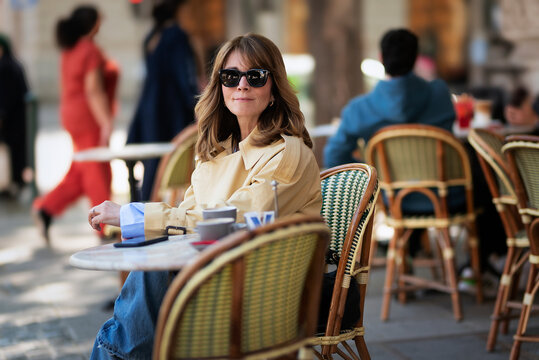 Sophisticated mature woman enjoying morning coffee at a european sidewalk cafe