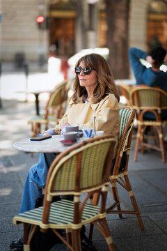 Sophisticated mature woman enjoying morning coffee at a european sidewalk cafe