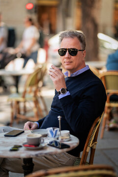 Stylish mature man enjoying coffee at a sidewalk cafe