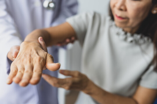 Doctor assesses senior woman's wrist and arms mobility and pain during clinical consultation, evaluating joint function and possible arthritis or injury in a healthcare.