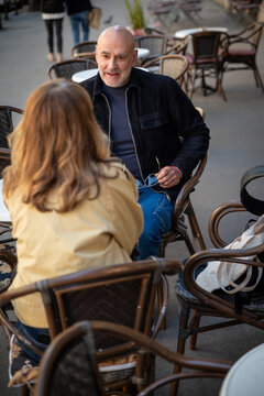 Mature couple enjoying conversation at an outdoor sidewalk cafe