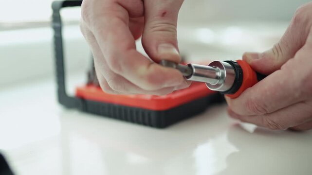Close-up of a handyman in a jumpsuit assembling a multi-bit screwdriver, professional DIY project, 4K footage
