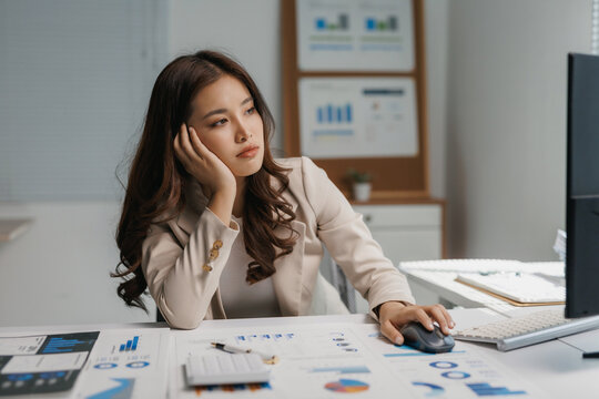 Young Asian businesswoman slumping at her desk, feeling tired and unmotivated, experiencing burnout and stress while working in the office