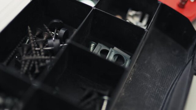 Close-up of a multi-bit screwdriver, nails, and boots in a plastic organizer, house makeover concept, 4K footage