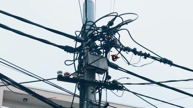 Electrical utility pole showing a short circuit causing sparks and a small fire on tangled wires and cables, representing issues with aging infrastructure and energy distribution