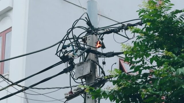 Electrical pole short circuit ignites overhead power lines, emitting sparks and smoke and posing a serious urban fire and electrocution hazard near streets and buildings