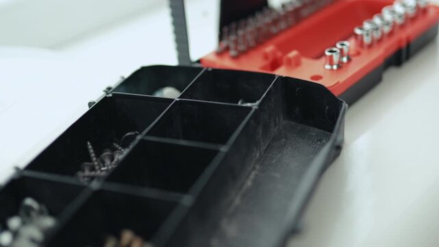 Close-up of a multi-bit screwdriver, nails, and boots in a plastic organizer, house makeover concept, 4K footage