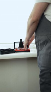 Close-up of a handyman in a jumpsuit assembling a multi-bit screwdriver, professional DIY project, 4K footage