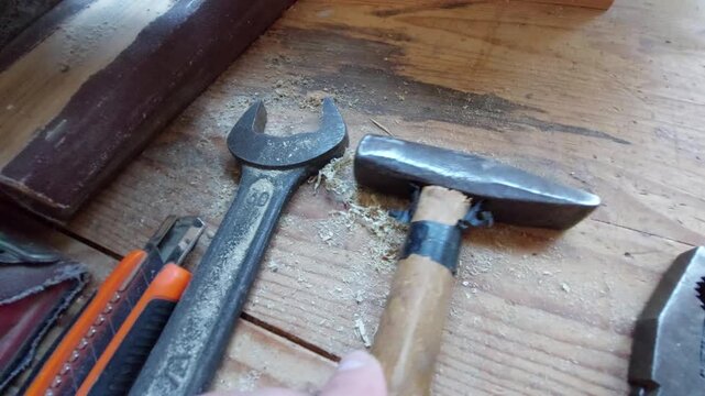 Top view of old hand tools including a hammer, wrench, and pliers on a wooden background