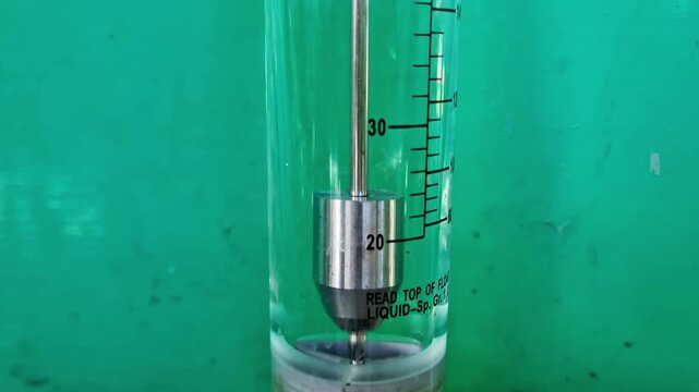 Precision rotameter flow measuring instrument showing metal float and GPM scale, green background.
