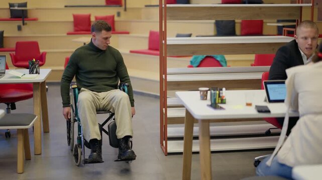 A man in a wheelchair moves confidently through a contemporary office environment. He is part of a diverse team working collaboratively in an accessible workspace.
