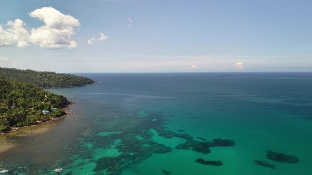 Aerial coastal view of reef patches turquoise water forested shoreline and open sea near Bacungan Palawan Philippines