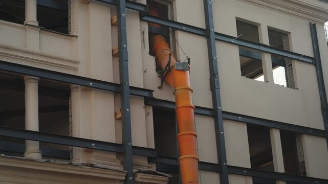 Waste chute used in construction demolition garbage. Suspended sections of a construction garbage chute on the facade of a historic building undergoing renovation. Safe waste disposal.