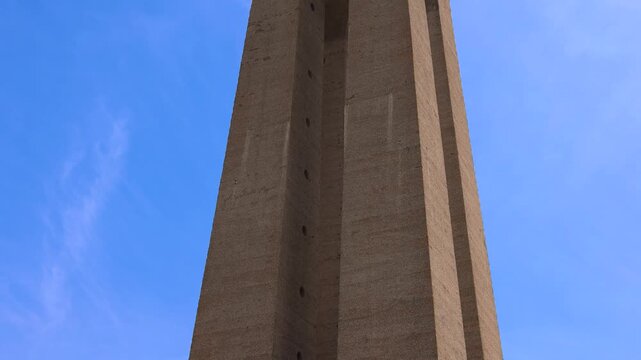 Low angle view of the Santuario de Cristo Rei sanctuary of christ the king monument with a stone cross in the foreground under a blue sky in Almada Portugal