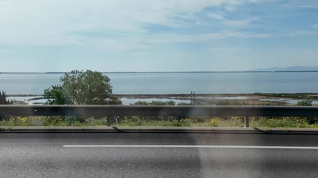 Driving shot filmed from inside a car passing by the stunning natural reserve near Peyriac-de-Mer, close to Narbonne in the south of France The calm waters and natural shoreline of this protected area